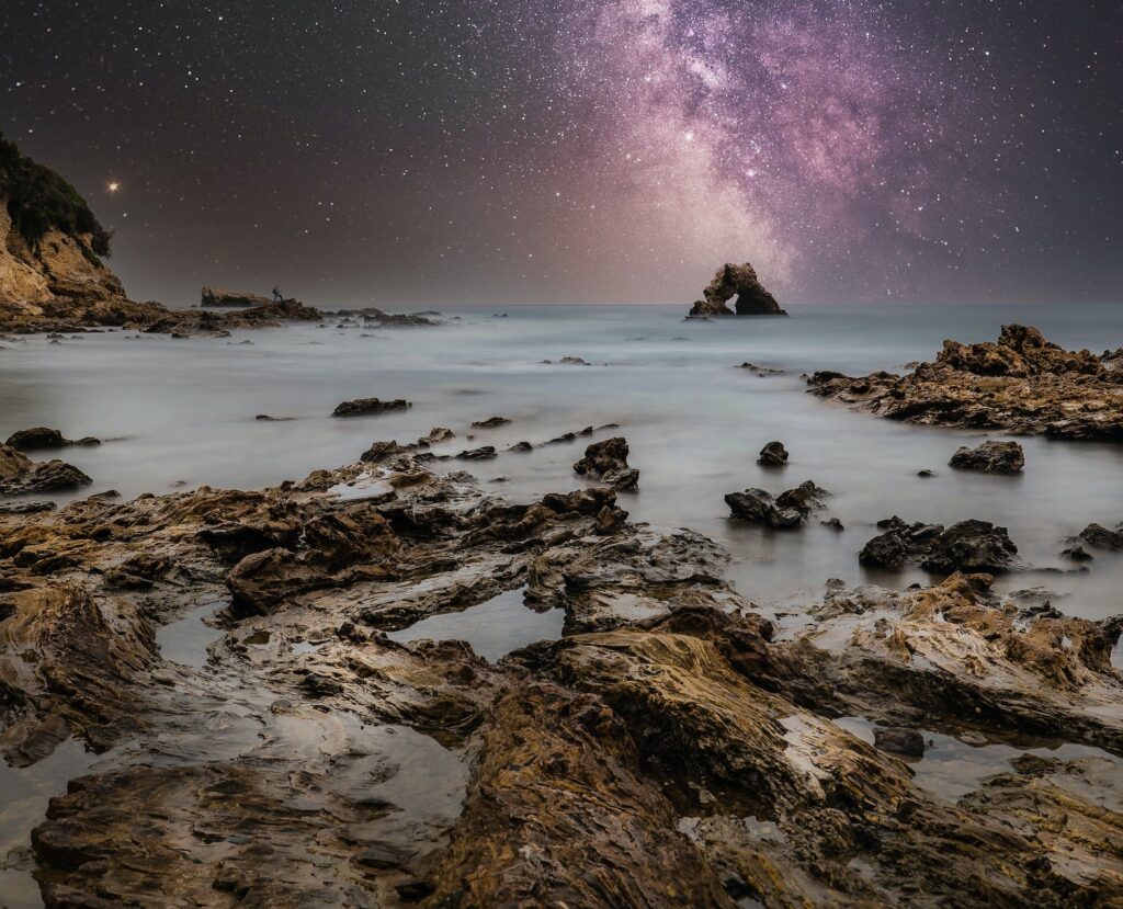 rocky coastline with purple starry skies