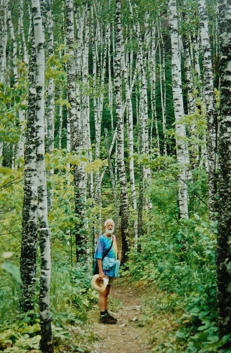 man in bright shirt on a trail surrounded by aspen trees