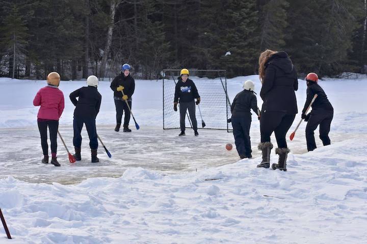 group of women playing broomball on a frozen lake