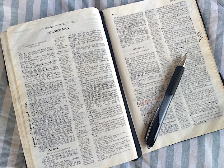 a Bible opened up to the book of Colossians, a pen sits on the Bible