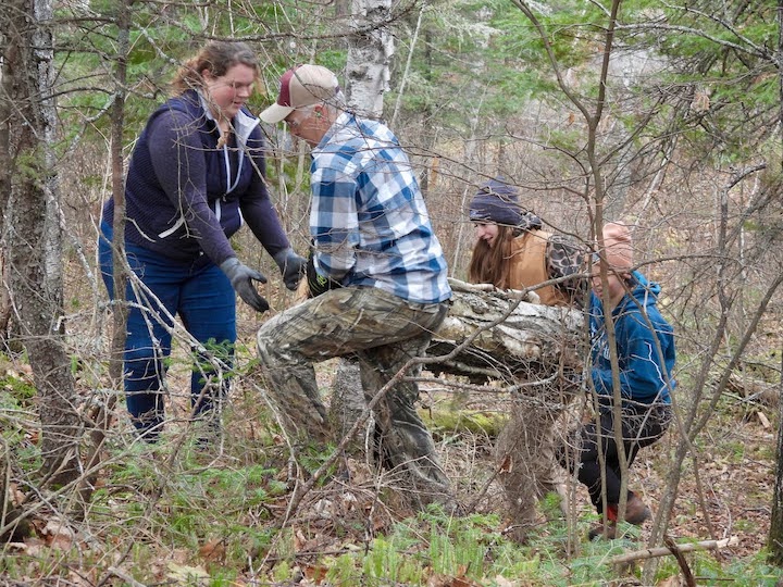 A group hauling a large log up a hill