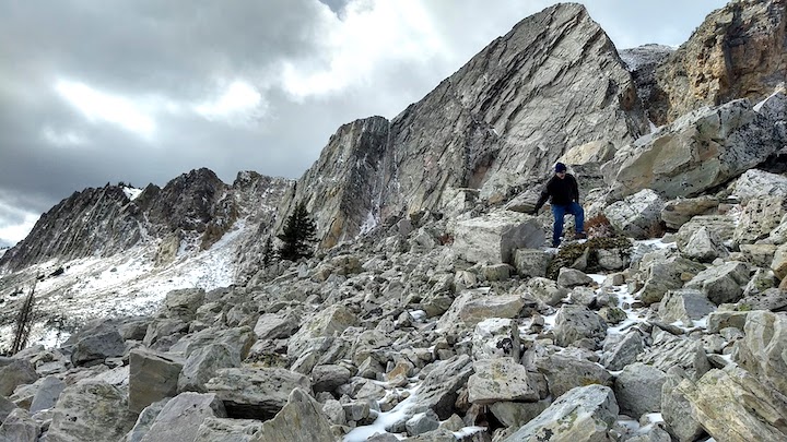 A man walks across boulders in the mountains