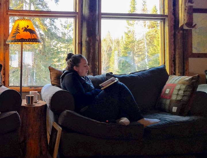 woman in an easy chair at a lodge, reading her Bible