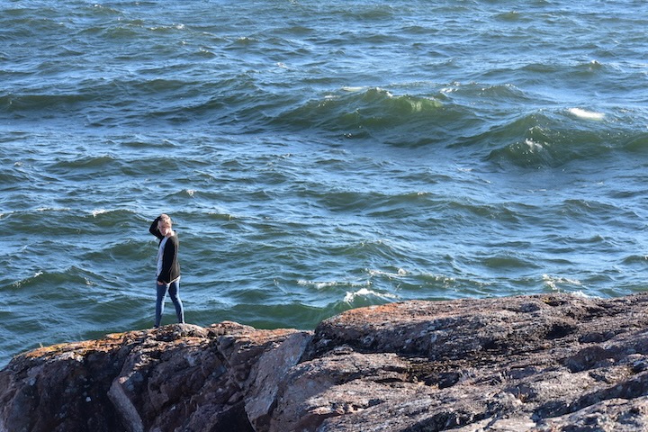 woman standing next to lake superior on rocks