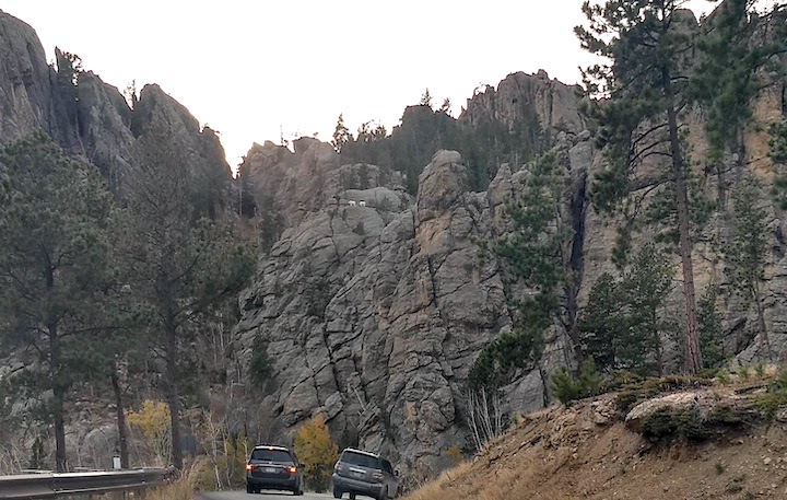cars stop to see a couple mountain goats on the high rocks