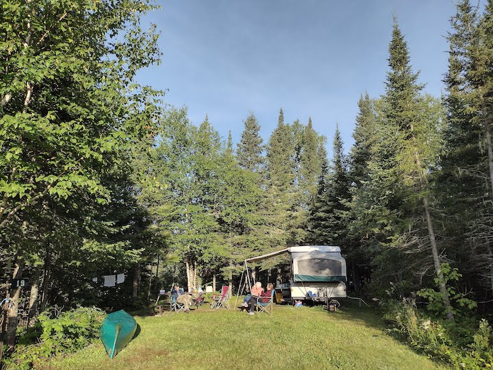 campers with a pop-up camper at a spacious wooded campsite