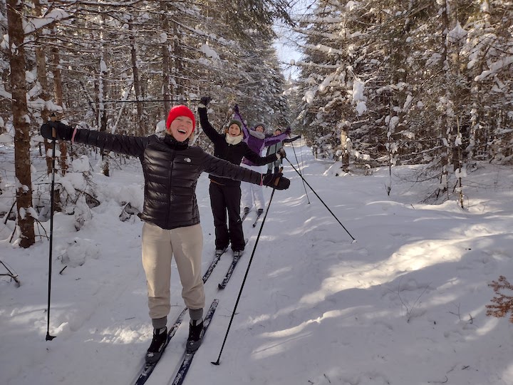 four women cross country skiing in the woods