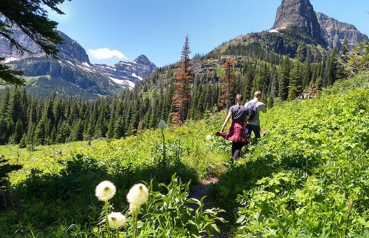 two hikers on the Twin Falls trail in Glacier, mountains in the background