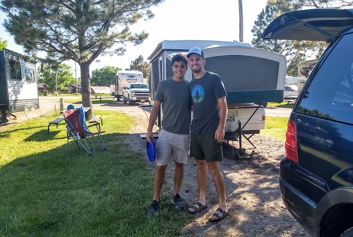 two young men at an RV campsite