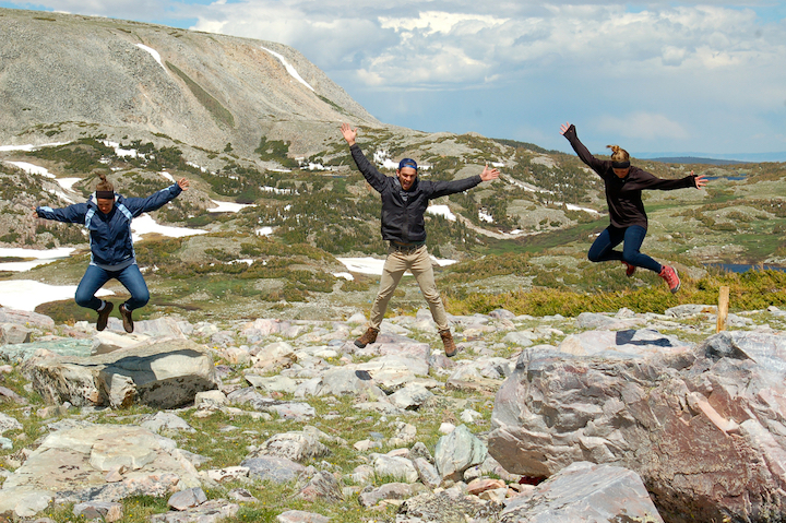 three people jump high in the mountains
