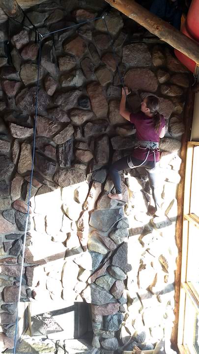 woman climbing a 2-story stone fireplace
