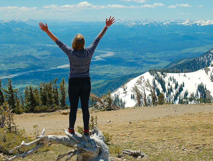 woman raising her hands on a mountain top