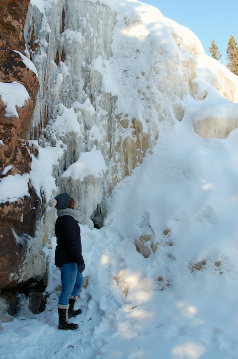 woman standing next to a frozen waterfall