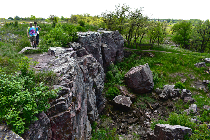 two people hiking along the top of a short cliff