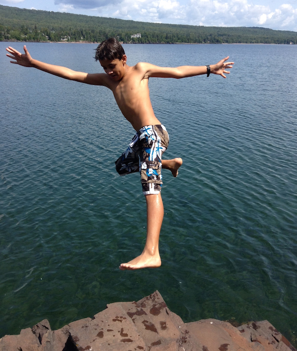young boy falling off a rock ledge into Lake Superior