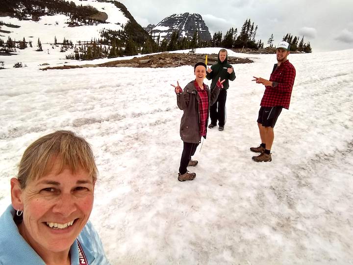 four adult hikers on the snow at Logan Pass