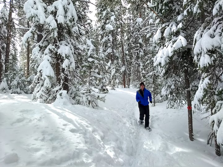 woman running in her snowshoes through a pine wood