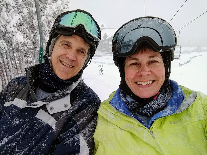 two people on a chairlift at a ski resort, lots of snow