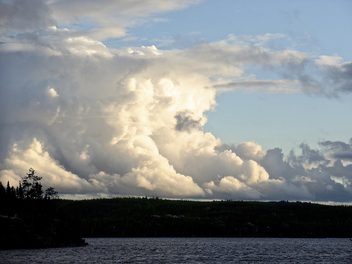 towering clouds reflect the sun's light over a lake