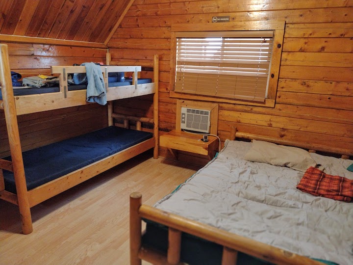 inside of a camping cabin, shows bunks and queen bed