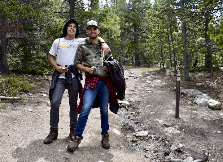 two young men on a mountain trail in the woods, smilling