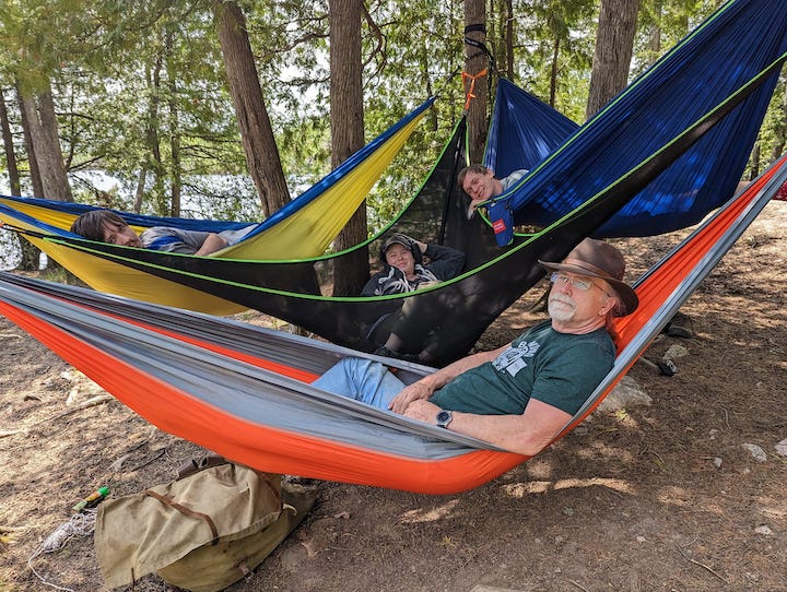 four family members in their hammocks at a campsite