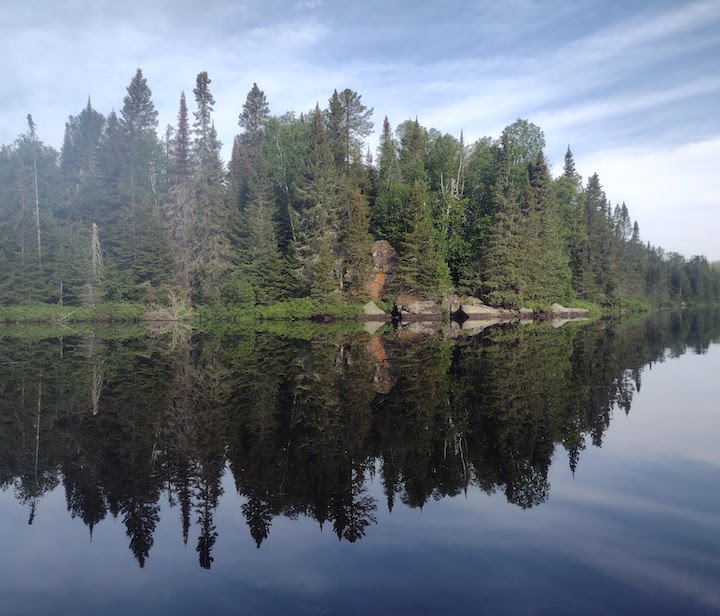 perfect reflection of trees and rocks on a calm lake