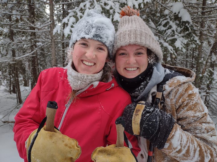 two young women in the snowy woods, covered in snow