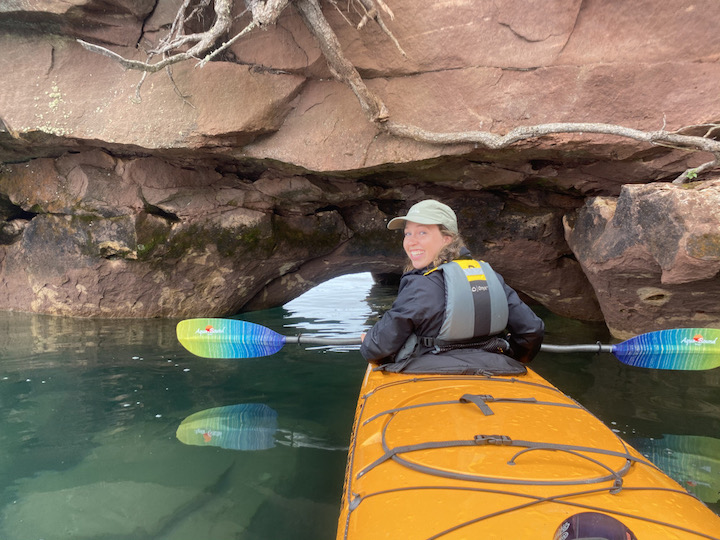 the author in the front of a sea kayak amid a sea cave