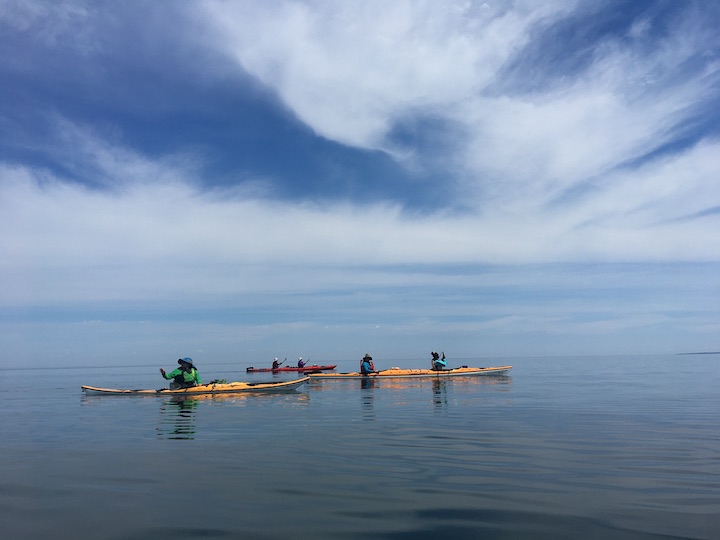 three sea kayaks on a calm Lake Superior