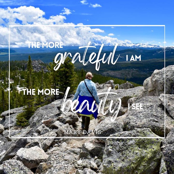 "the more grateful I am the more beauty I see" with image of woman hiking on a mountaintop, overlooking more mountains
