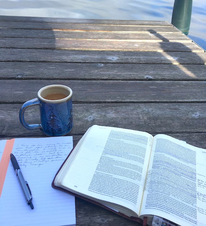 coffee, bible and journal on a dock at a lake