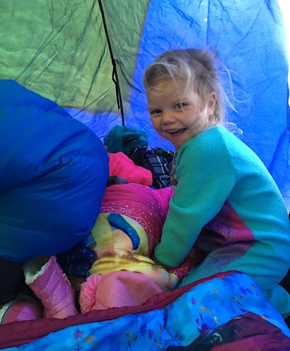little girl in her jammies inside their tent