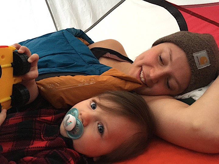 young mom with her toddler laying down inside their tent