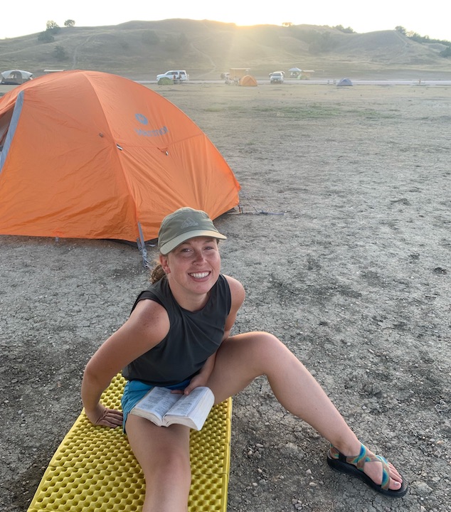 The author, Emilie, reads her Bible on her slipping outside just outside her tent in a desert-y environment