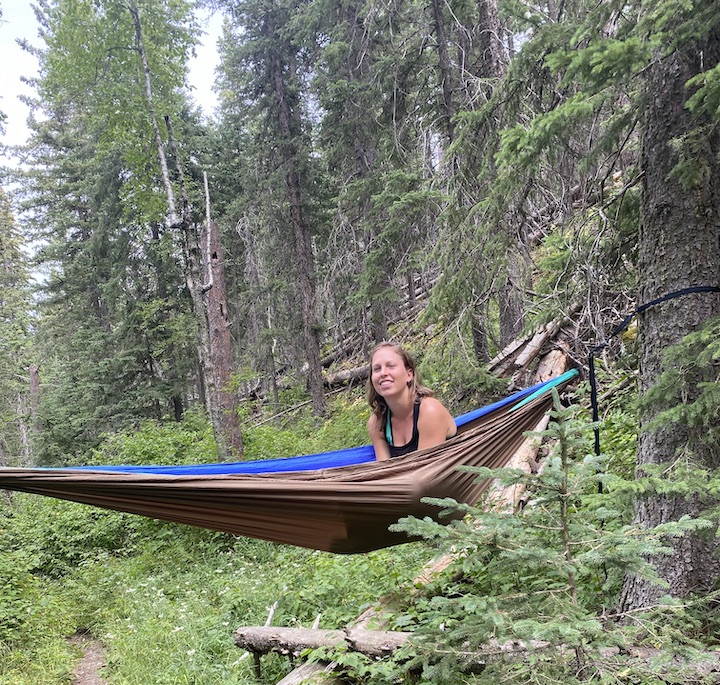 woman sitting in her hammock in the woods