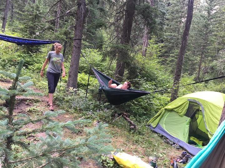 two women with hammocks and a tent at their wooded campsite
