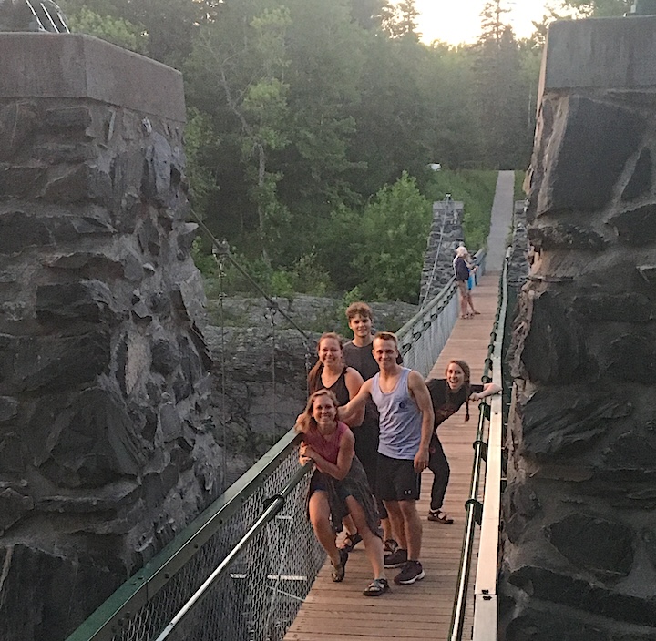 group of friends on a narrow bridge, smiling