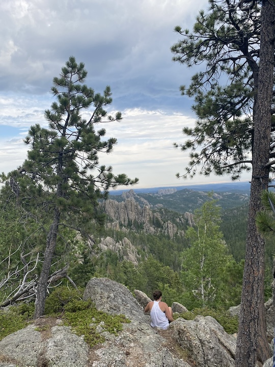 woman sits on a cliff overlooking the Black Hills